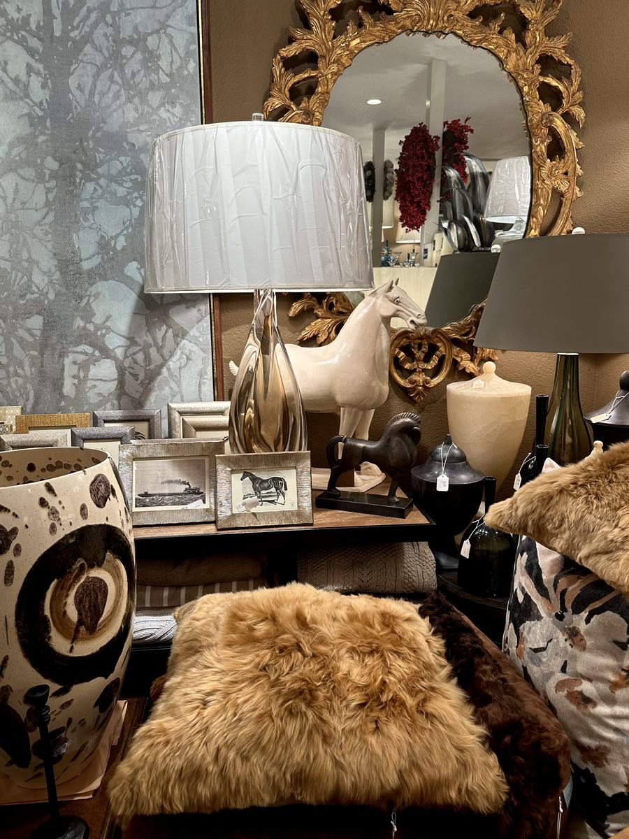 A console vignette with a gilt mirror, sculptural lamp and ceramic horse.