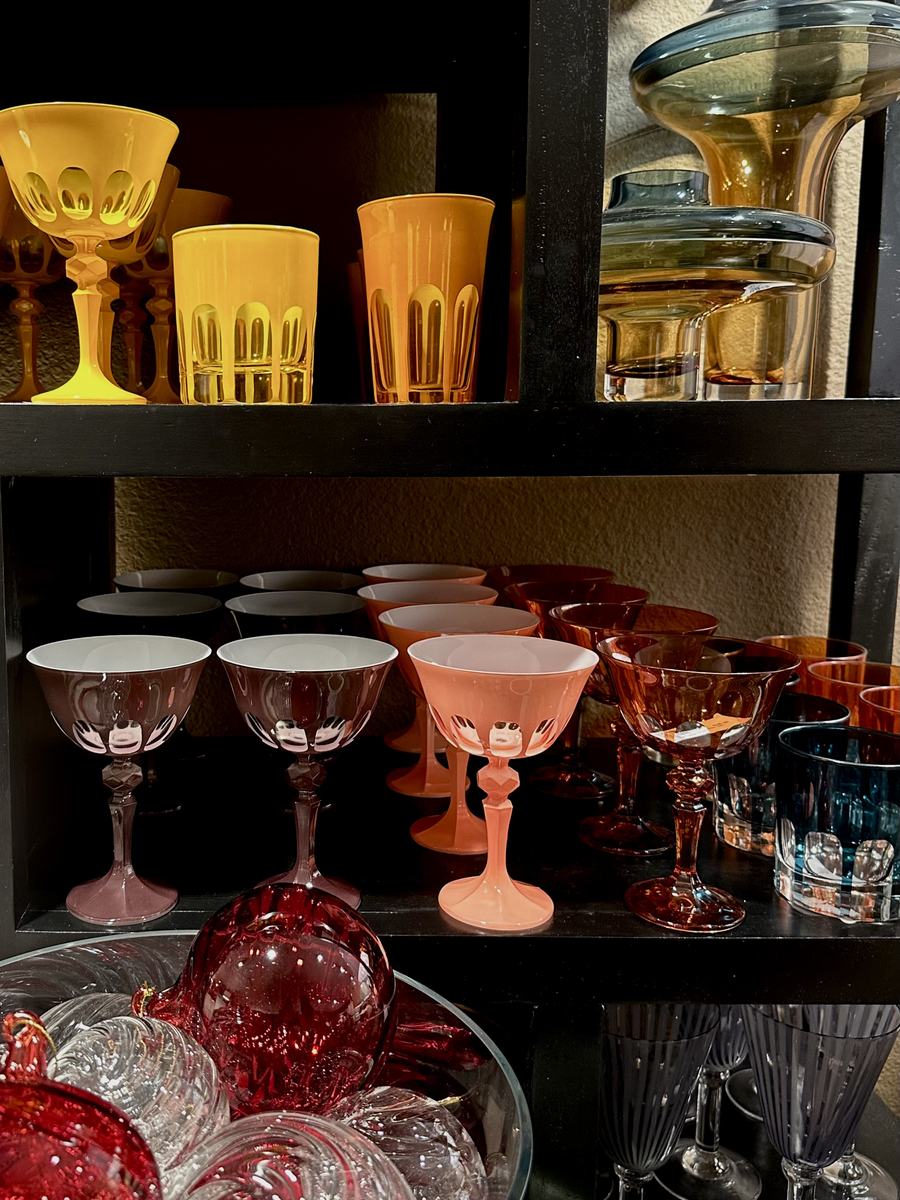 Shelves of coloured glassware in amber, rose and smoke.
