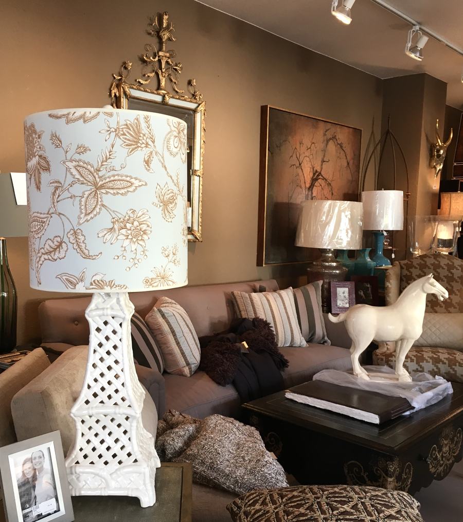 A white lattice lamp with toile shade beside a sofa and ceramic horse.