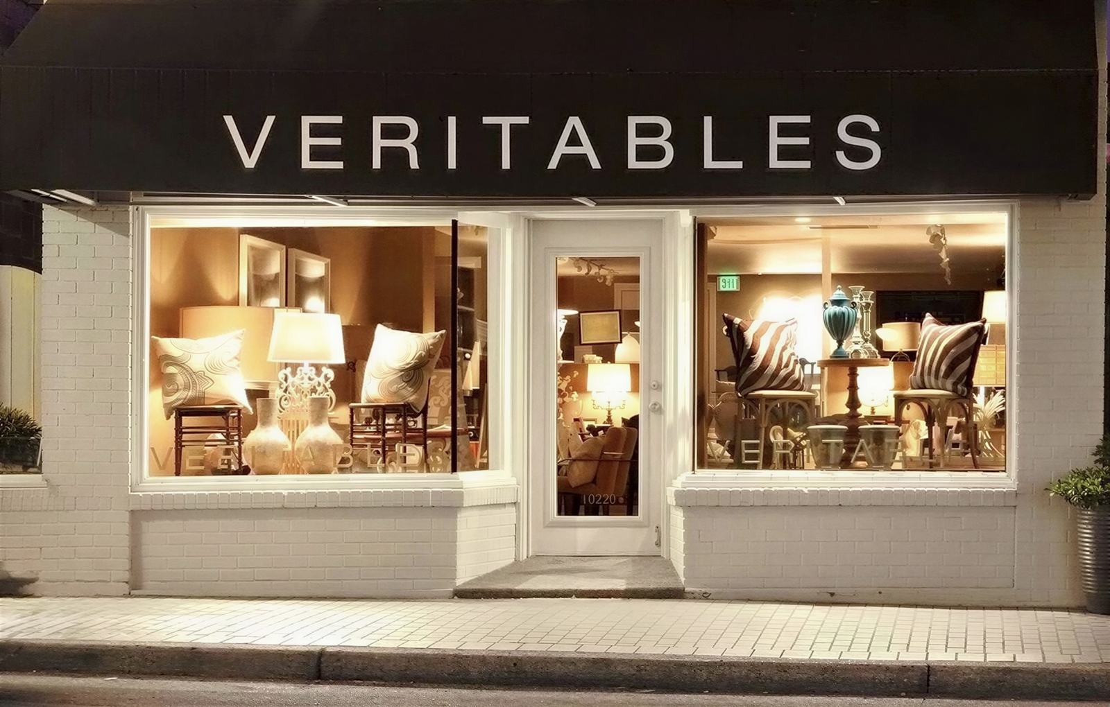 The Veritables storefront on Main Street at night, both windows lit.